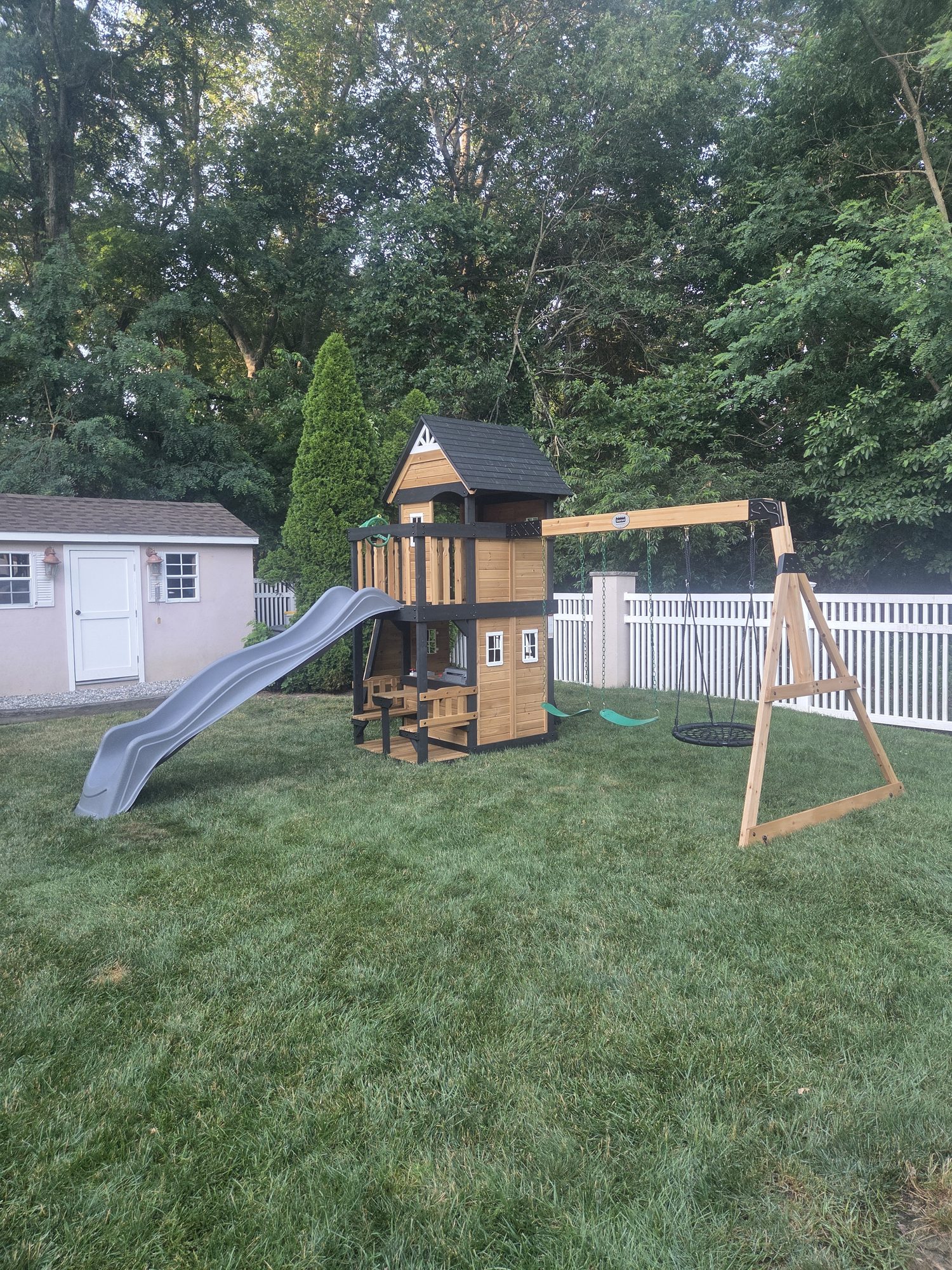 Completed wooden backyard playset with a slide and swings.