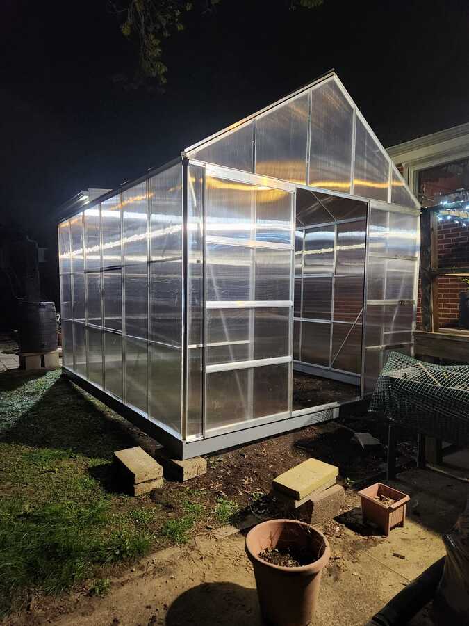Completed greenhouse glowing in a backyard at night