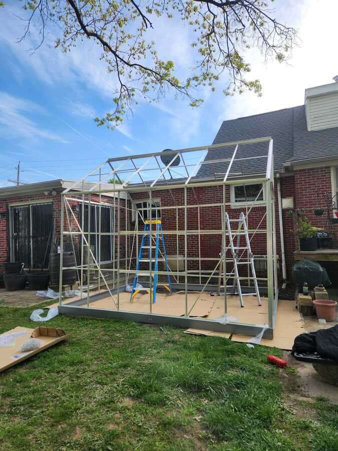 Greenhouse frame standing in a backyard during assembly