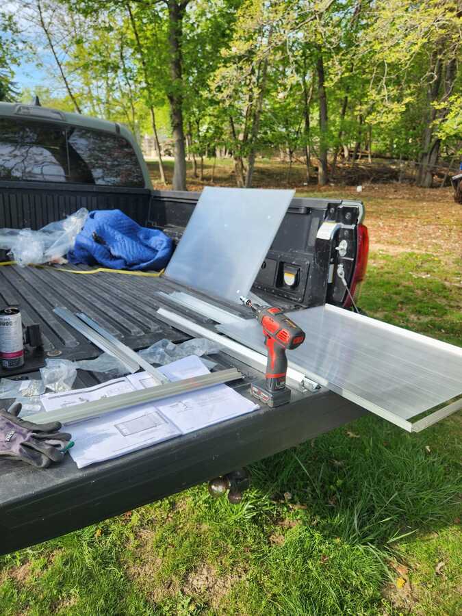 Greenhouse panels, tools, and assembly plans arranged in a pickup bed