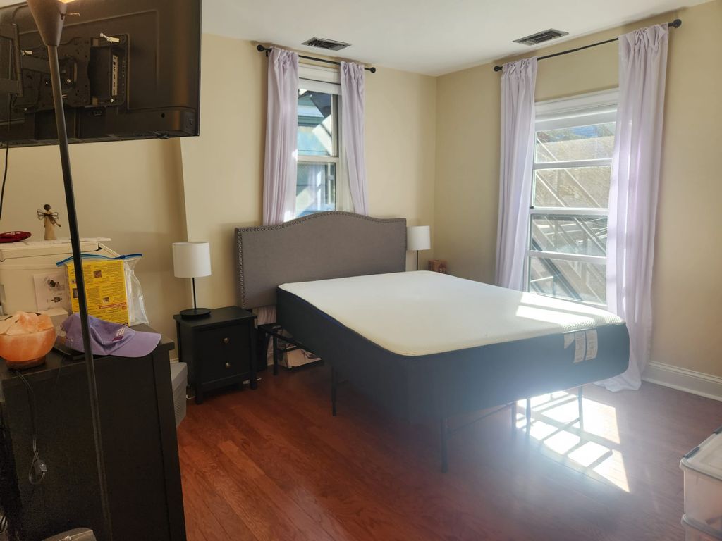 A bed, dresser, and nightstands placed in a bright bedroom.