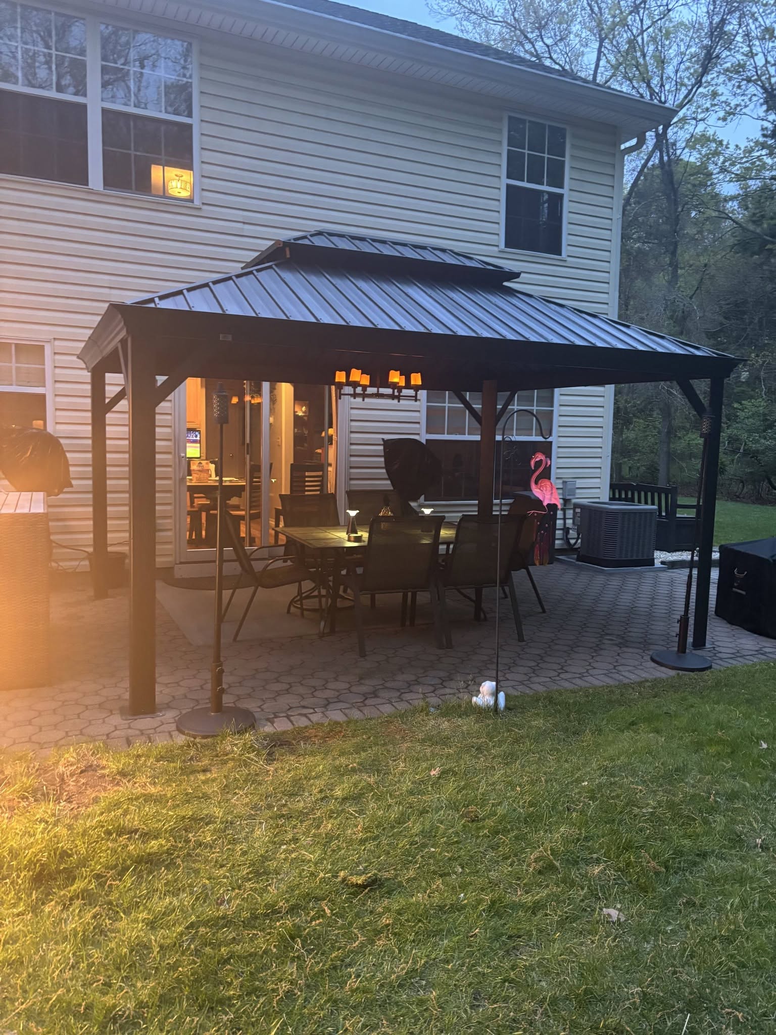 A completed dark metal gazebo furnished with a patio table and chairs.