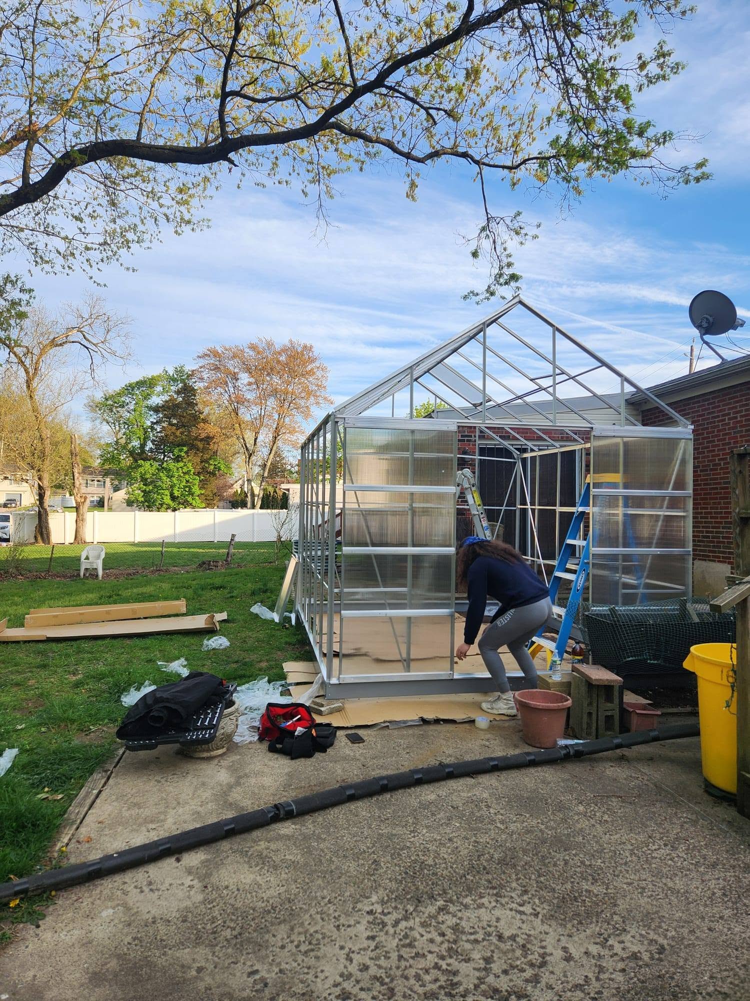 A Butch Services crew member assembles a greenhouse in a backyard.