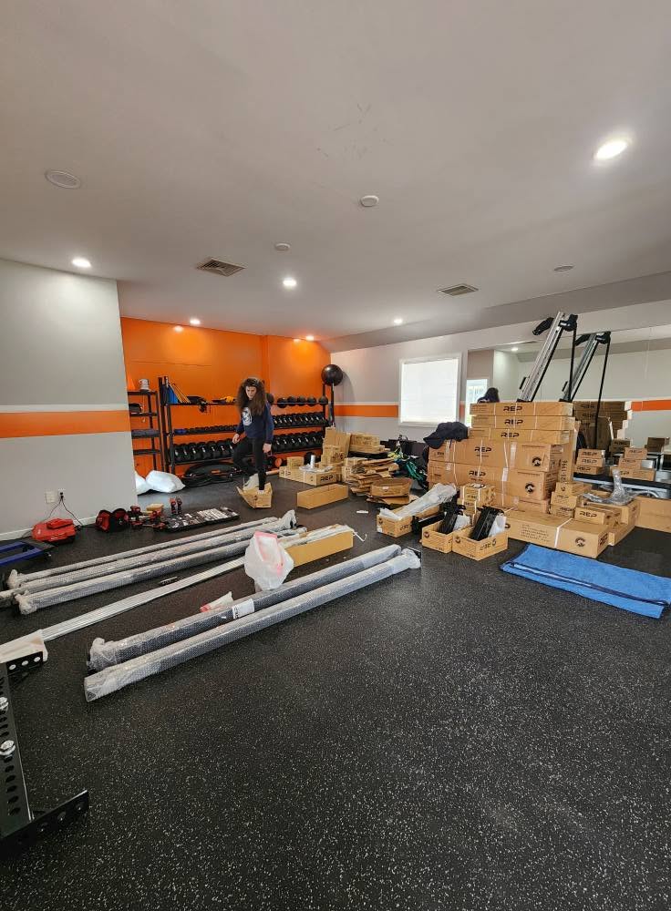A Butch Services crew member organizes parts and tools during a gym equipment installation.