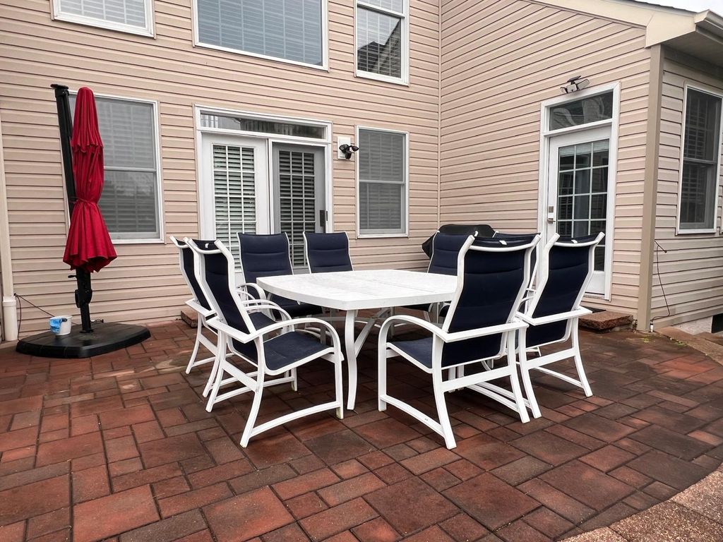 A patio table, chairs, and umbrella arranged on a brick patio.