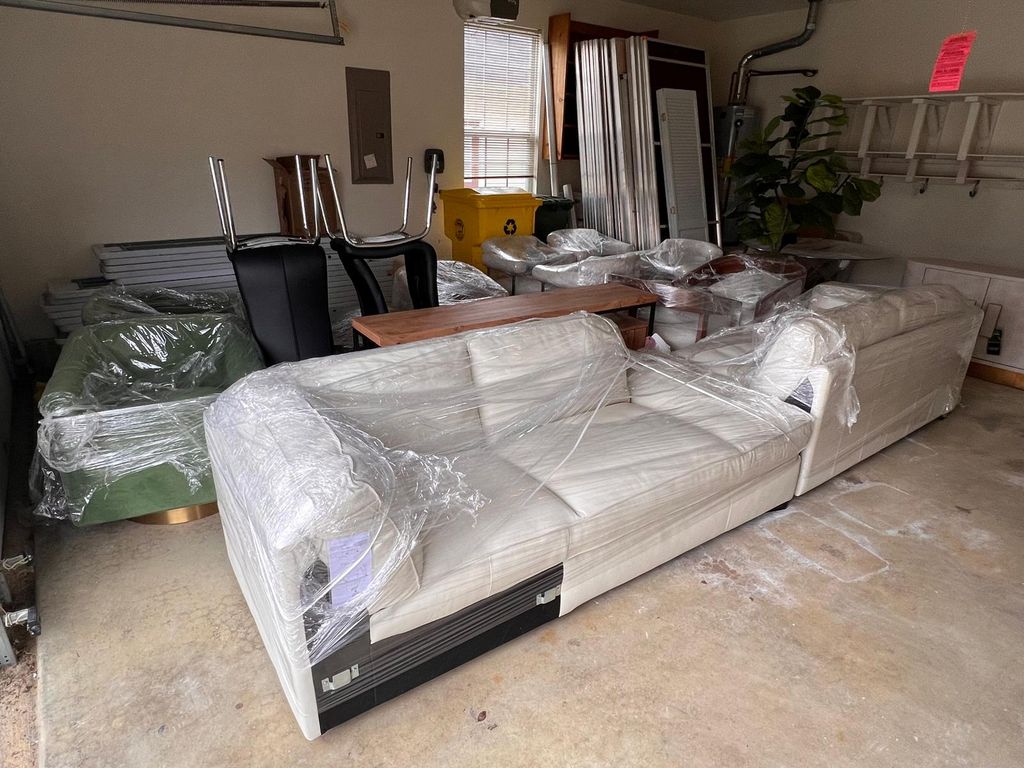 Sofas and furniture wrapped in protective material inside a room.